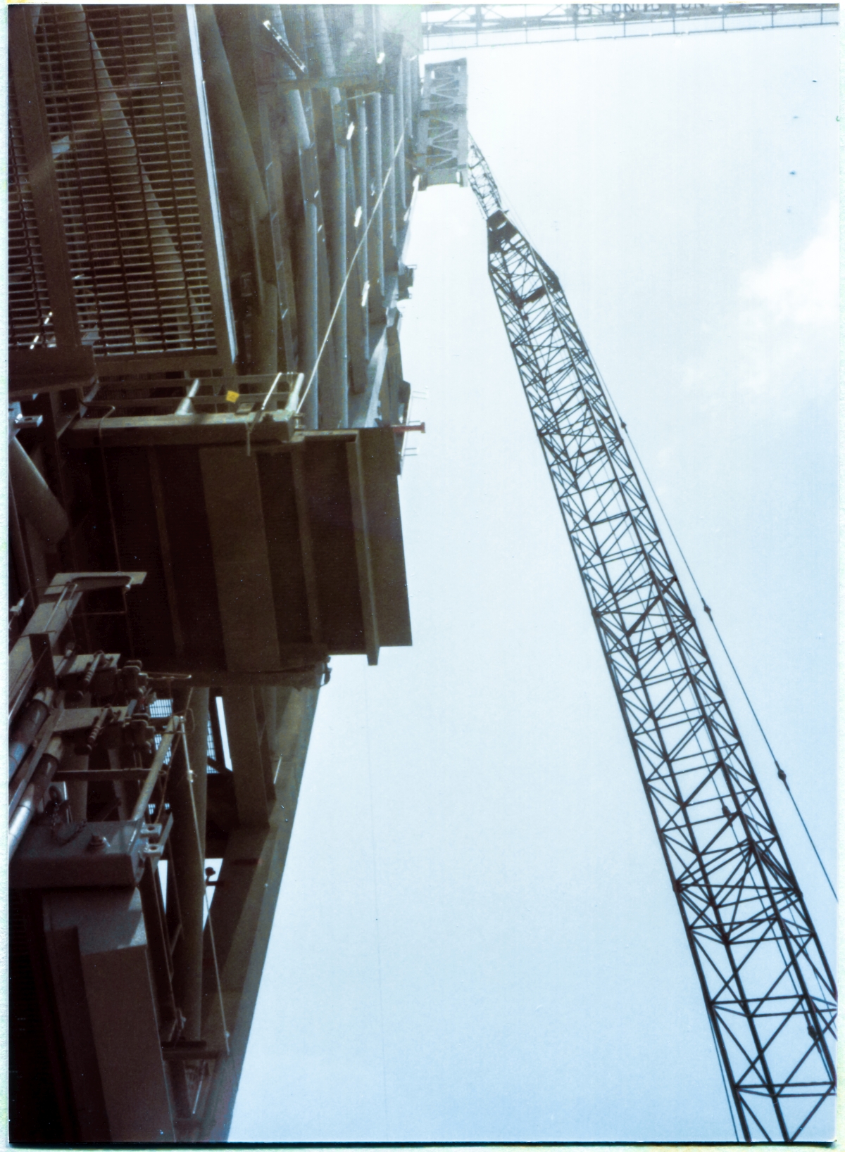 Image 077. GOX Arm Strongback at its final elevation at the top of the Fixed Service Structure at Space Shuttle Launch Complex 39-B, Kennedy Space Center, Florida, viewed from directly beneath it, just outside the perimeter envelope of the FSS on Side 1. You're bent way over backwards, trying to hold your camera pointed straight up, while squinting through the viewfinder composing your frame, and it's disorienting, and it makes you want to topple over and fall flat on your ass, and properly centering the goddamned frame turns out to take a lot longer than you want it to, and meanwhile, far above your deeply-stupid head, Death stops for a moment and considers you, and decides whether or not it wants to take you, and before it has a chance to decide it does, and then do so, you hit the shutter release, snatch the camera back down away from your eye, and get the hell out of there on your fastest legs, to safety beneath the main structure of the FSS where falling objects cannot get you. Photo by James MacLaren.